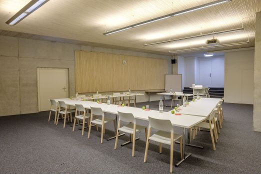 Heller Meetingraum mit U-förmiger Bestuhlung, Whiteboard und Beamer – ideal für Workshops, Schulungen und kleinere Business-Events am Thunersee. ©Seaside Spiez Seminarraum mit U-Form-Bestuhlung, Tischen und Whiteboard