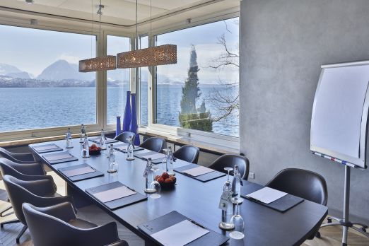 Heller Konferenzraum mit gedecktem Tisch, Glasfront und Blick auf den Thunersee – ideal für Workshops und Business-Meetings in der Region Thun. ©Beatus Moderner Meetingraum am Thunersee mit Seeblick und Flipchart