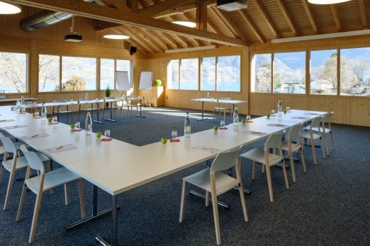Moderner Tagungsraum mit viel Holz, großen Fenstern und U-Setup – ideal für Meetings, Workshops und Seminare in der Region Thun-Thunersee. ©Seaside Spiez Heller Seminarraum mit U-Bestuhlung und Blick auf die Berge am Thunersee