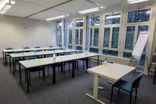 Seminarraum im U-Setup mit Flipchart und gro&szlig;en Fenstern f&uuml;r Tageslicht