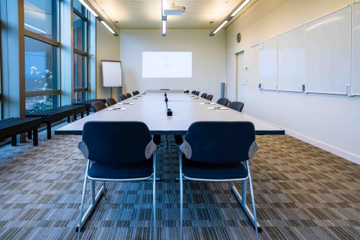 Heller, professioneller Konferenzraum mit großem Tisch, bequemen Stühlen und moderner Präsentationstechnik. Panoramafenster bieten Ausblick und viel Tageslicht, Whiteboards und Flipchart fördern produktive Meetings – ideal für Unternehmen im Raum Thun und Umgebung. Modern ausgestatteter Konferenzraum Tokyo