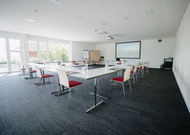 Moderner Meetingraum mit U-Tisch, Leinwand und grossen Fenstern – ideal für Workshops, Schulungen und Business-Events am Thunersee. ©Solbad Heller Seminarraum mit U-Form, Beamer und Tageslicht in der Region Thunersee