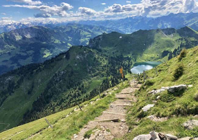 Bergwanderweg mit Stufen und Panoramablick auf Gipfel und Bergsee bei Thunersee
