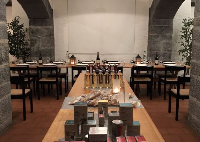 Ein stilvoll gedeckter Verkostungstisch in einem charmanten Gewölberaum mit Steinbögen. Im Vordergrund stehen regionale Spezialitäten und Produkte, Getränke sind elegant arrangiert. Perfektes Ambiente für Geschäftsanlässe, Teamevents und exklusive Firmenveranstaltungen in der Thunersee-Region. Stimmungsvolles Degustationserlebnis im historischen Gewölbe