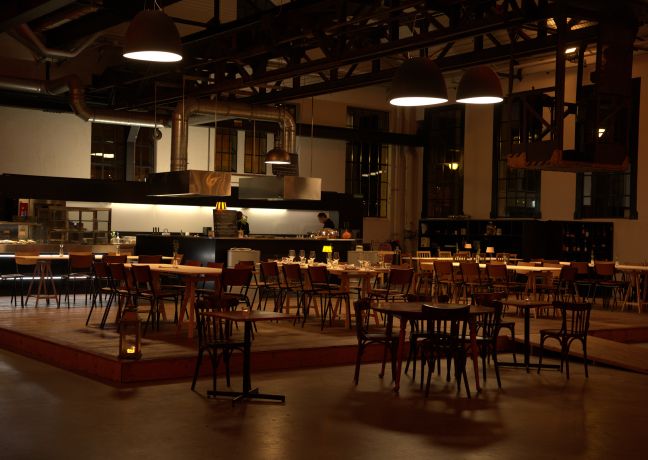 A stylish event restaurant with an open kitchen and tables set for dinner