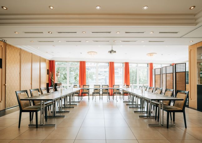Moderner Seminarraum für Meetings am Thunersee: U-Form mit Tischen, bequeme Stühle, grosse Fensterfront und warme Akzente. ©Hotel Krone Heller Konferenzraum mit U-förmiger Bestuhlung und Tageslicht