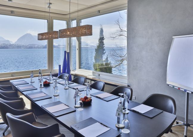 Heller Konferenzraum mit gedecktem Tisch, Glasfront und Blick auf den Thunersee – ideal für Workshops und Business-Meetings in der Region Thun. ©Beatus Moderner Meetingraum am Thunersee mit Seeblick und Flipchart