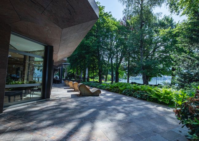 Moderne Hotelterrasse mit stilvollen Loungemöbeln, umgeben von üppigem Grün und direktem Blick auf den Thunersee. Perfekte Umgebung für entspannte Business-Pausen, Networking oder kleine Meetings mitten in der Natur. Ideale Eventlocation für Firmen und Organisationen in exklusiver Lage. Sonnige Hotelterrasse am Thunersee