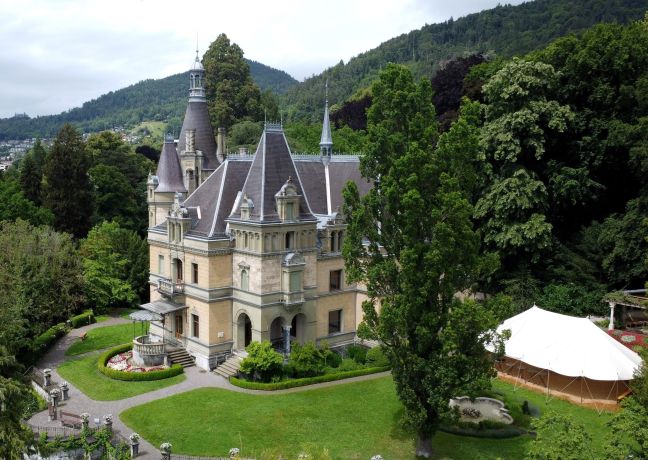 Das historische Schloss Hünegg in Hilterfingen liegt idyllisch inmitten einer weitläufigen Parkanlage am Ufer des Thunersees. Das elegante Herrenhaus besticht durch seine märchenhafte Architektur, umgeben von grüner Natur – ideal für exklusive Firmenanlässe und inspirierende Meetings im Berner Oberland. Schloss Hünegg in Hilterfingen
