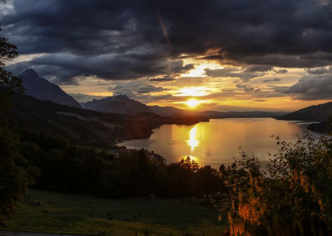 Sonnenuntergang &uuml;ber dem Thunersee mit Alpenpanorama und dramatischen Wolken