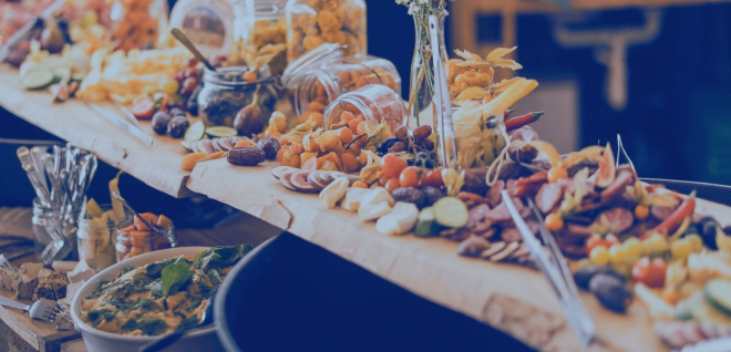 Apéro-Riche-Buffet auf Holzbrett mit Fingerfood und Blumen dekoriert