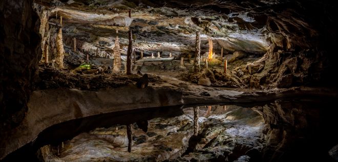 Stimmungsvolle Tropfsteinhöhle mit beleuchteten Stalagmiten und Spiegelung