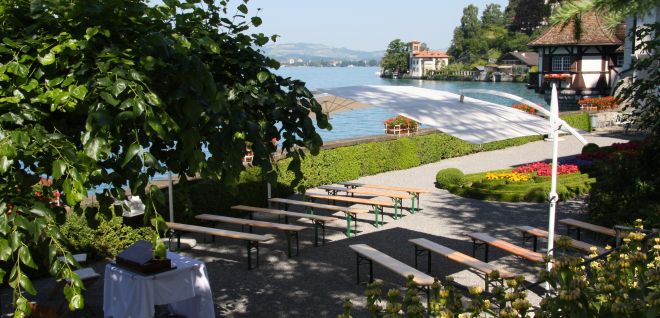 A terrace on Lake Thun with tables, benches and views of the lake and mountains