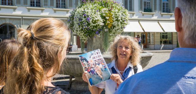 Guided tour of Thun: guide shows brochure on a sunny square