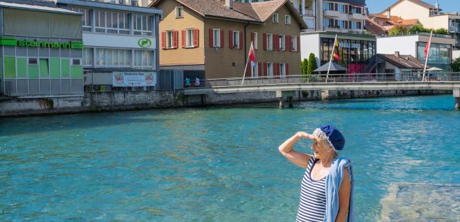 Frau am Ufer mit Blick auf Hafen und Altstadthäuser in Thun am Thunersee