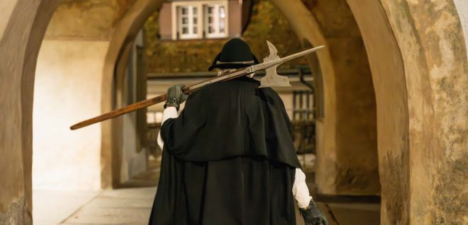 Nachtwächter mit Laterne unter historischem Torbogen in Thun