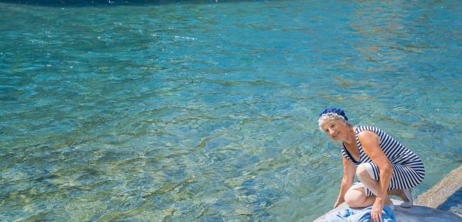 Frau am Ufer des Thunersees beim Abkühlen der Füsse im klaren Wasser