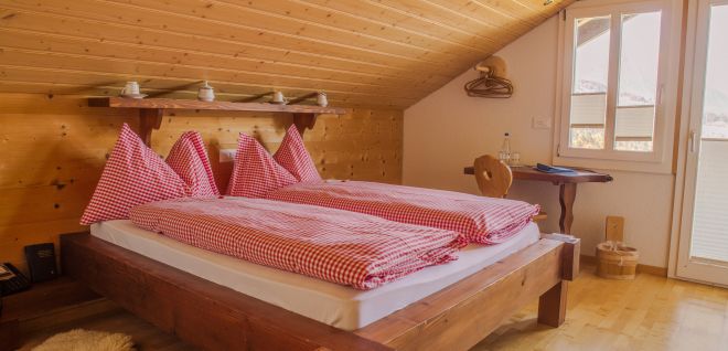 A cosy attic room with a wooden bed and red checked bed linen