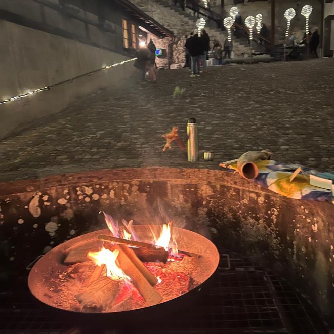 A fire pit in the evening with fairy lights in the background