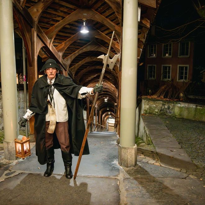 Nachtwächter mit Laterne unter überdachtem Holzsteg in Thun