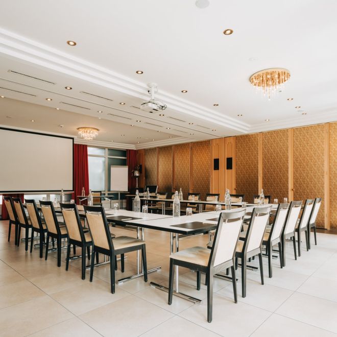 A bright seminar room with U-shaped seating and a projection screen