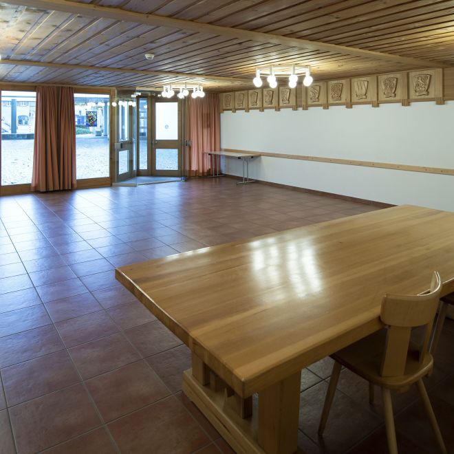 A bright seminar room with a wooden table, chairs and large windows in Spiez