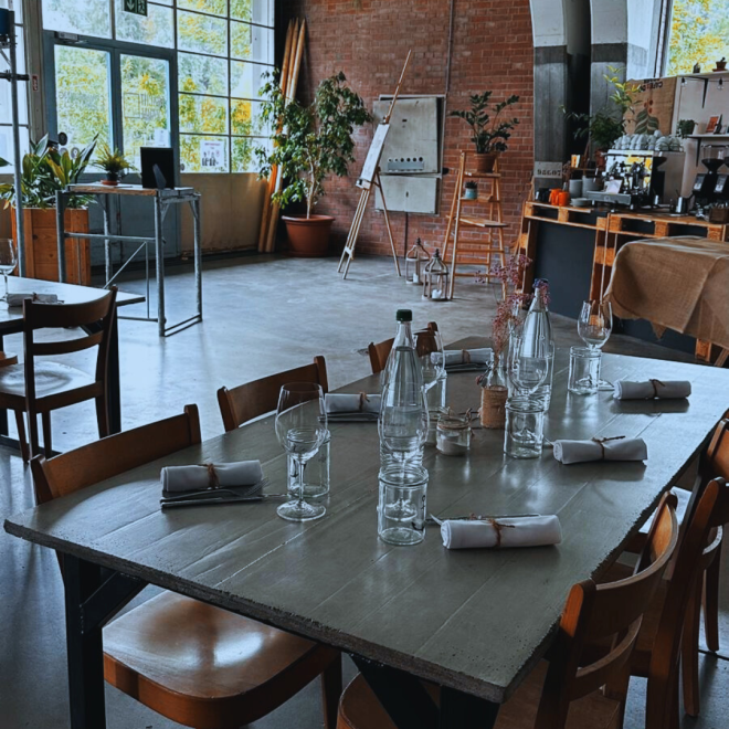 A set event table in a stylish industrial venue with a bar and tall windows in Thun