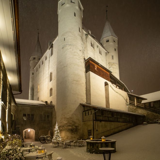 Schloss Thun im Winter bei Nacht mit verschneitem Innenhof und Lichtern