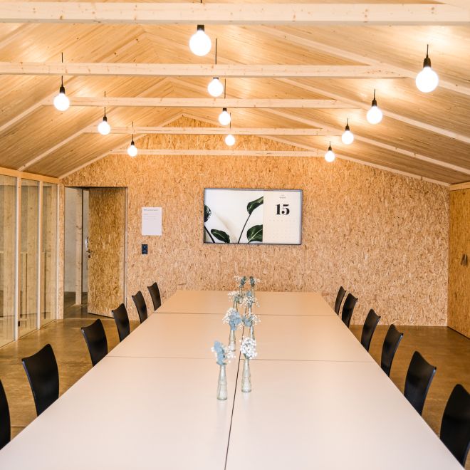 A bright seminar room with a long table and a wooden ceiling on Lake Thun